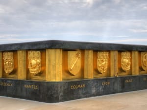 Golden stone monument with city crests at Hartmannswillerkopf memorial