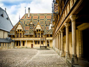 Interior courtyard of the Hospices de Beaune in Burgundy, with its famous patterned glazed tile roofs, half-timbered gallery and cobbled courtyard