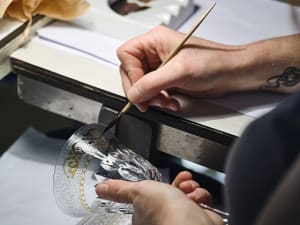 Artisan hand‑paints gold and white motifs on a Saint Louis crystal goblet