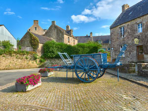 Traditional blue wooden cart in a cobbled square surrounded by stone houses in Locronan.