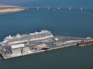 Aerial view of La Rochelle cruise terminal with a large cruise ship docked beside a long pier and coastal bridge in the background