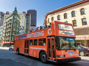 Orange double-decker Skyline Sightseeing tour bus on a San Francisco street with historic architecture