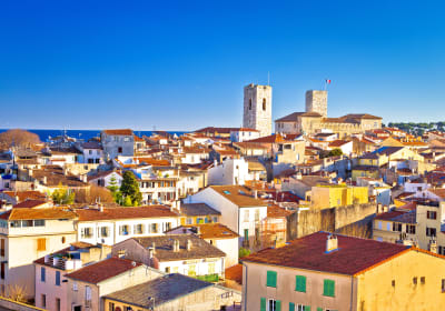 Panoramic view of Antibes Old Town with historic towers, terracotta rooftops and the Mediterranean Sea.