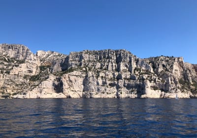 Boat cruising through the Calanques cliffs during a small group tour from Aix-en-Provence