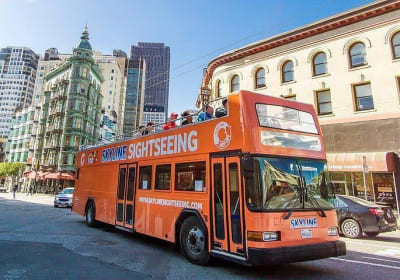 Orange double-decker Skyline Sightseeing tour bus on San Francisco street with historic buildings