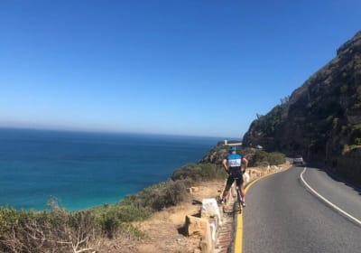 Photo of a cyclist who has stopped to enjoy the sea view on the coastal road above Noordhoek to Chapmans Peak.