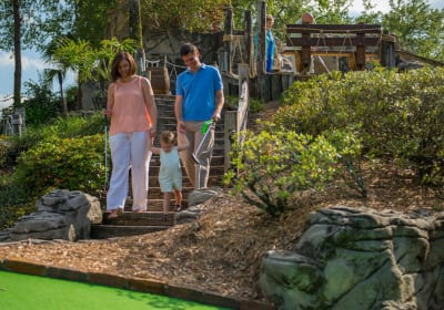 Family coming down steps to a mini golf hole - Pirates Cove Orlando