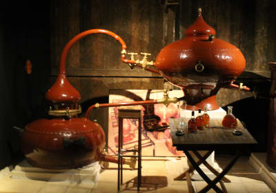 Traditional copper alembic still with bottles on a table in a Cognac distillery display