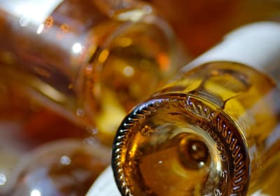 Close-up of the base of golden Sauternes wine bottles with warm amber reflections, Bordeaux