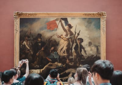 Visitors gathered in front of a large framed painting at the Louvre Museum