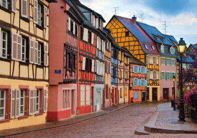  Row of colorful half-timbered houses along a cobblestone street in Colmar