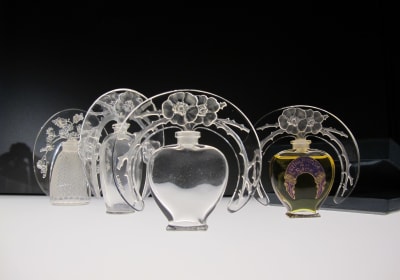 Row of ornate Lalique perfume bottles with etched floral halos