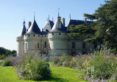 Flower-filled garden borders in front of the round towers and slate-roofed turrets of Château de Chaumont-sur-Loire in the Loire Valley, France.