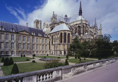 Palais du Tau beside Reims Cathedral, overlooking formal lawns, clipped shrubs, and a stone balustrade.