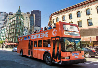 Orange double-decker Skyline Sightseeing tour bus on a San Francisco street with historic architecture