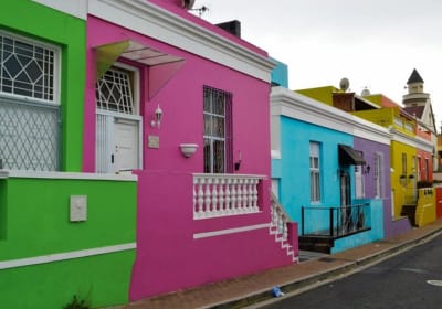 Photo of the bright, colourful houses in the Bo Kaap district of Cape Town, painted bright green, pink, turquoise, purple and yellow.