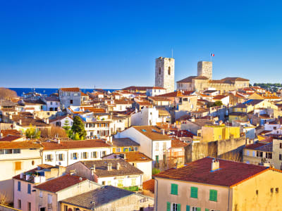 Panoramic view of Antibes Old Town with historic towers, terracotta rooftops and the Mediterranean Sea.