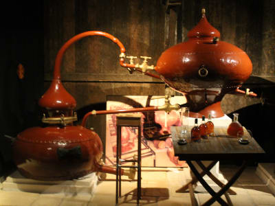 Traditional copper alembic still with bottles on a table in a Cognac distillery display
