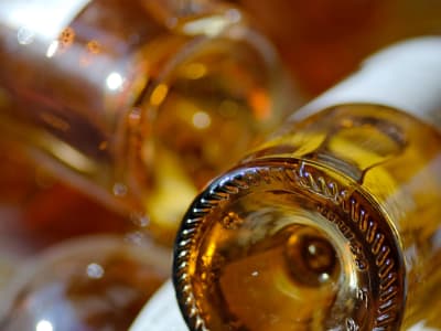 Close-up of the base of golden Sauternes wine bottles with warm amber reflections, Bordeaux