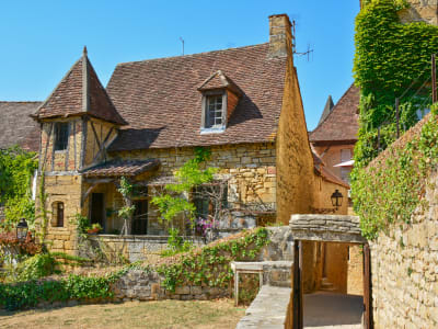 Historic stone house with ivy-covered walls and a narrow lane in Sarlat-la-Canéda on a sunny day