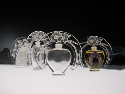 Row of ornate Lalique perfume bottles with etched floral halos