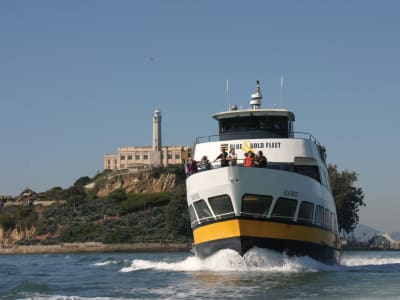 Blue and Gold Fleet ferry boat approaching Alcatraz Island with lighthouse visible on rocky shore