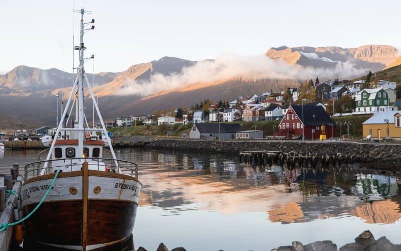 Boats docked in Siglufjörður harbor with colorful buildings