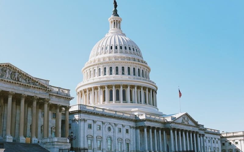 U.S. Capitol dome and neoclassical facade under a blue sky