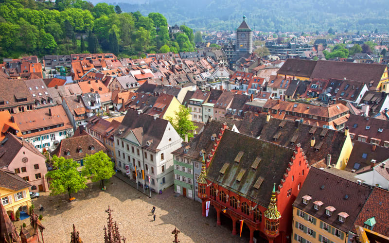 Aerial view over Freiburg rooftops and main square towards forested hills