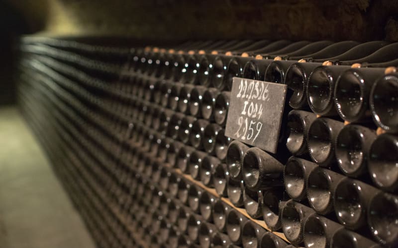 Champagne bottles stacked horizontally beside a handwritten cellar marker at Moët & Chandon in Épernay.
