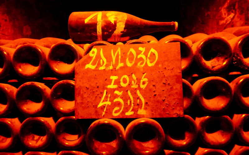 Stacked Champagne bottles and a handwritten cellar marker illuminated by amber light at Moët & Chandon in Épernay.