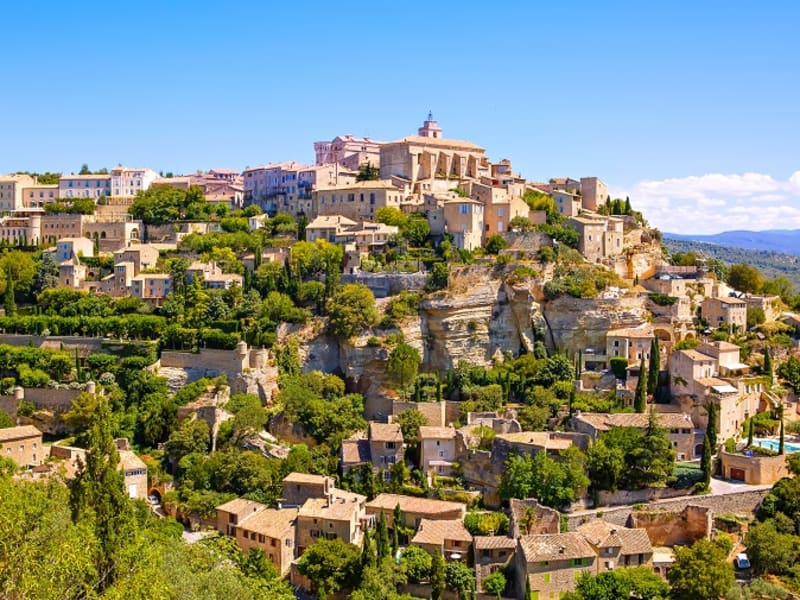 Panoramic view of Gordes hilltop village with honey-colored stone buildings cascading down cliff in Luberon Provence France