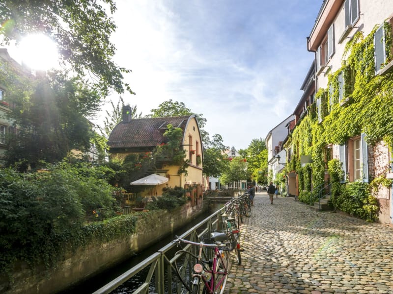 Sunny cobbled street with bikes along a canal in Freiburg old town