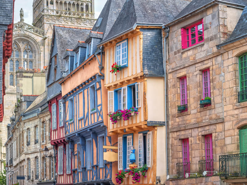 Row of colorful half‑timbered houses in Quimper old town with cathedral tower rising behind.