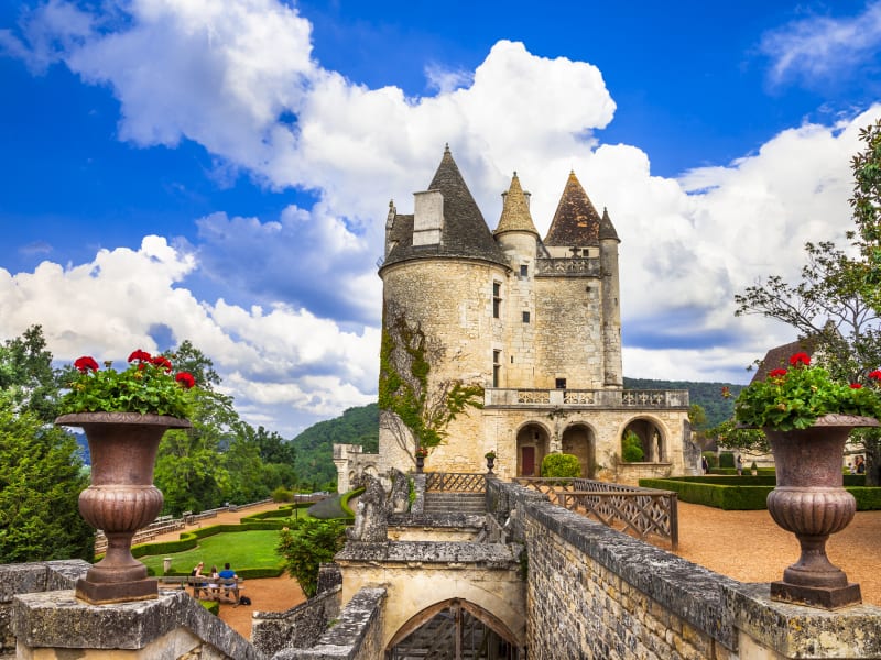 Château des Milandes with stone towers, formal gardens and flower-filled urns in the Dordogne
