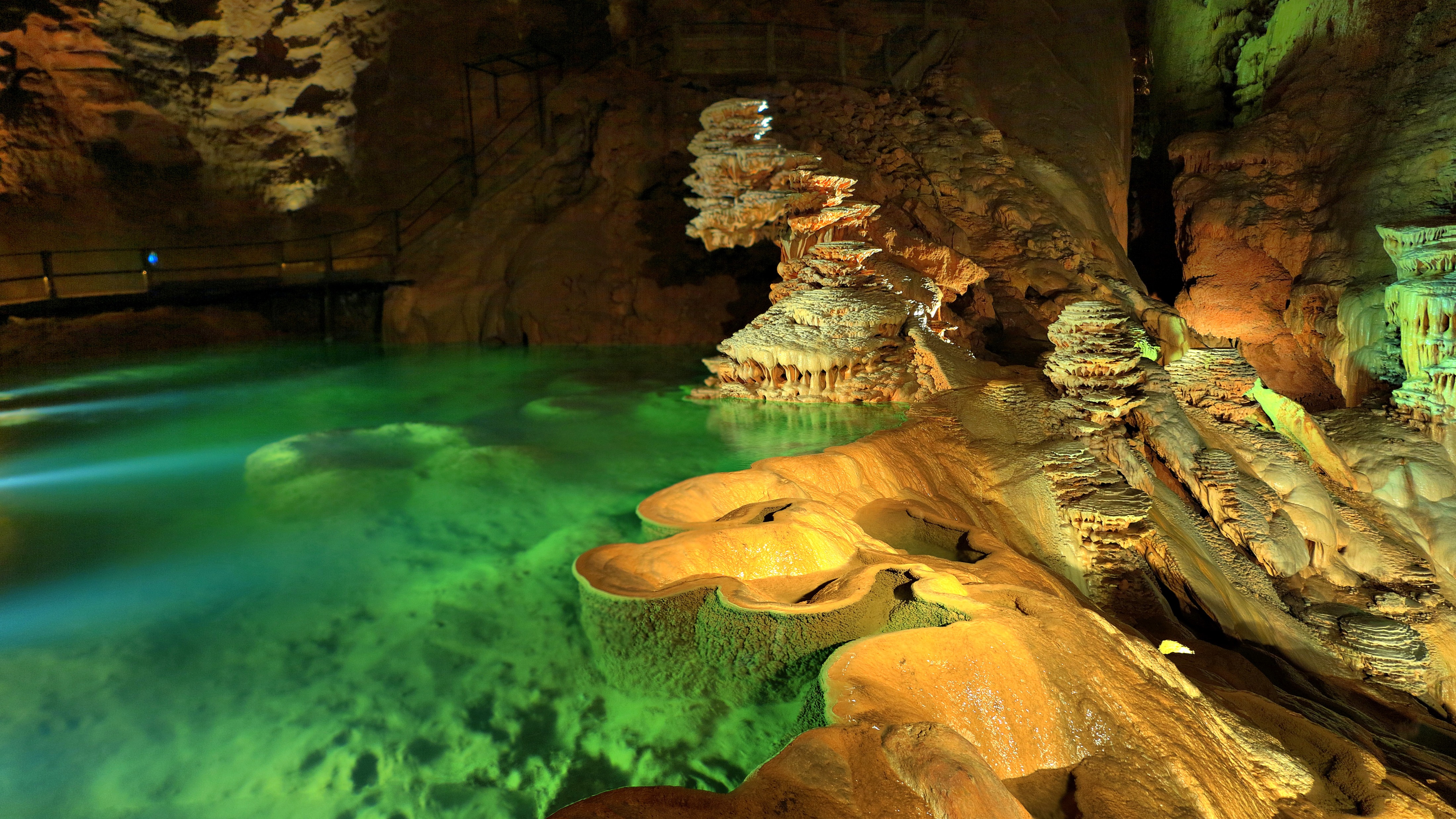 Turquoise water and illuminated limestone formations inside the Gouffre de Padirac underground cave in southwest France.