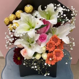 Graduation Floral Box of lilies, Pink Roses and Gerbera. Ferrero Rocher chocolate balls and gypsophila filling in a black box.