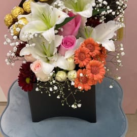 Graduation Floral Box of lilies, Pink Roses and Gerbera. Ferrero Rocher chocolate balls and gypsophila filling in a black box.