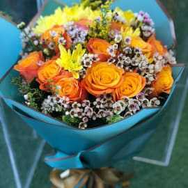 Bouquet of orange roses, solidago and yellow chrysanthemum in an elegant blue wrapping. 