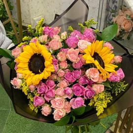 Bouquet of Sunflowers, dark light pink roses, solidago and eucalyptus in black wrapping. 