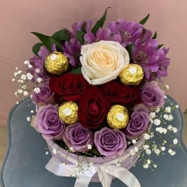 This beautiful and delicate arrangement contains purple roses surrounded by purple alstroemeria and red roses and a White rose in the middle with baby's breath filling and Ferrero Rocher chocolate bal