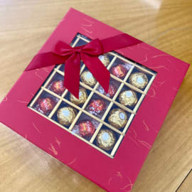 Elegant red box of Ferrero Rocher and Lindt chocolates with a red ribbon, perfect for gifting