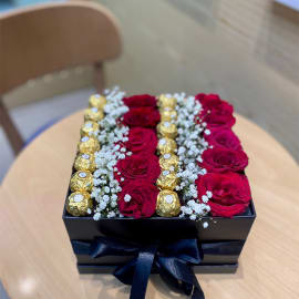 A beautiful arrangement of red roses, baby's breath, and Ferrero Rocher chocolates in a stylish flower box