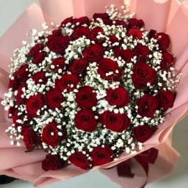 Stunning bouquet of 50 vibrant red roses, elegantly contrasted with delicate white baby's breath and lush green foliage