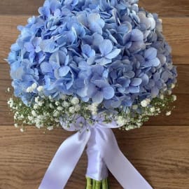 Close-up of a delightful bridal bouquet with blue hydrangea blooms and baby breath filling, representing beauty.