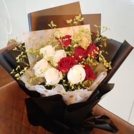 A stunning bouquet of red and white roses, elegantly wrapped in black and white.