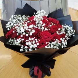 Romantic bouquet featuring 24 red roses, white baby's breath, and stylish black wrapping