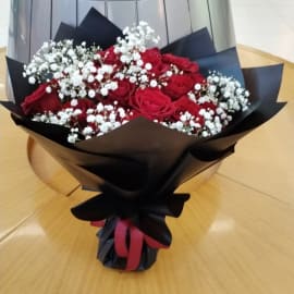 Romantic bouquet featuring 24 red roses, white baby's breath, and stylish black wrapping