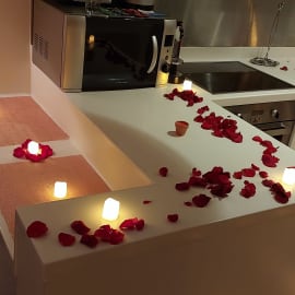 Heart-shaped rose petal arrangement on bed with candles