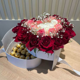Beautiful flower arrangement with chocolates in a heart-shaped box.